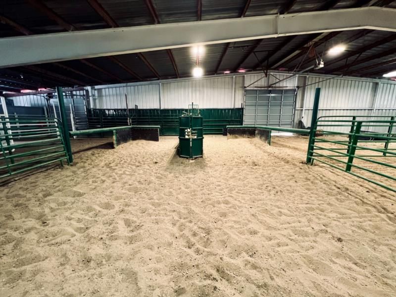 A dirt arena with a green fence and a barrel in the middle.