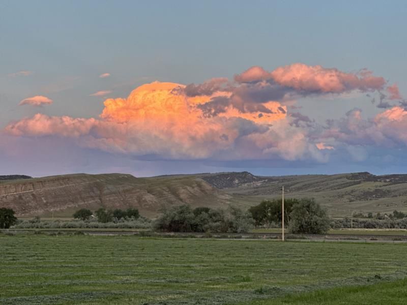A sunset over a grassy field with mountains in the background.