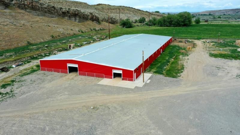 An aerial view of a large red barn in the middle of a field.