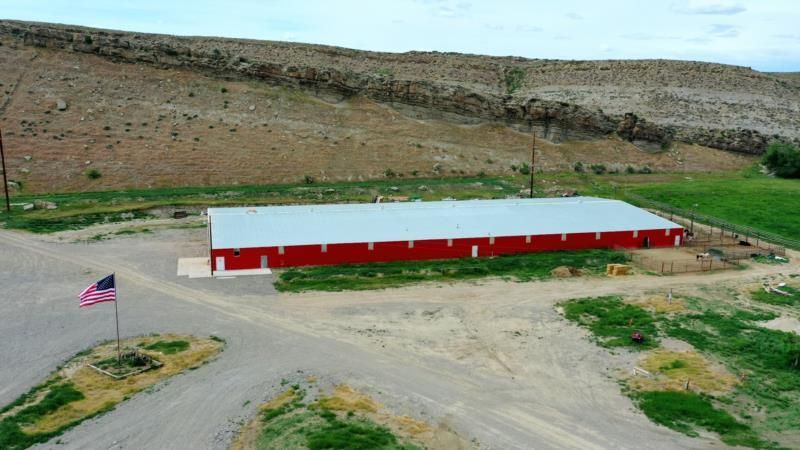 An aerial view of a large red barn with a flag in front of it.