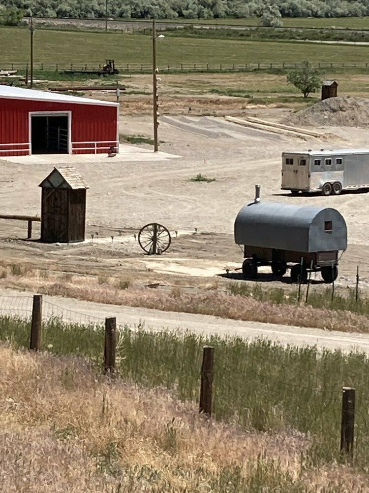 A trailer is parked in a field next to a red barn.