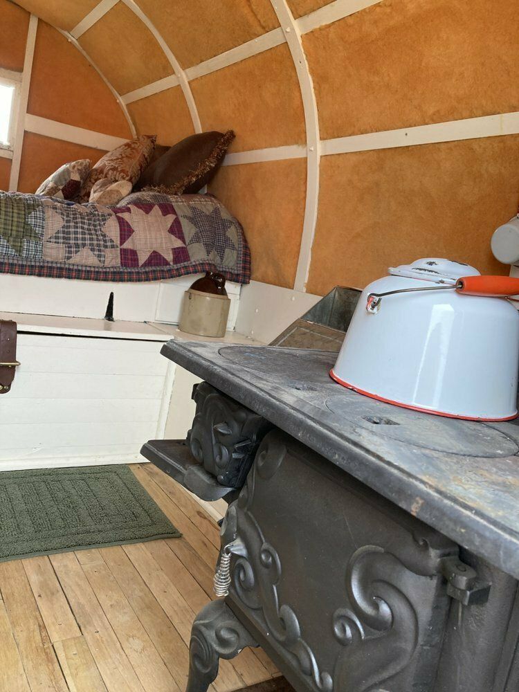 A wagon with a bed and a pot on the stove.