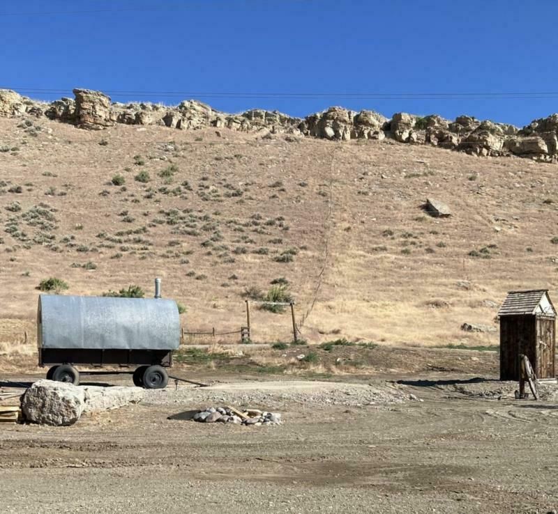 A trailer is parked in the desert next to a wooden outhouse