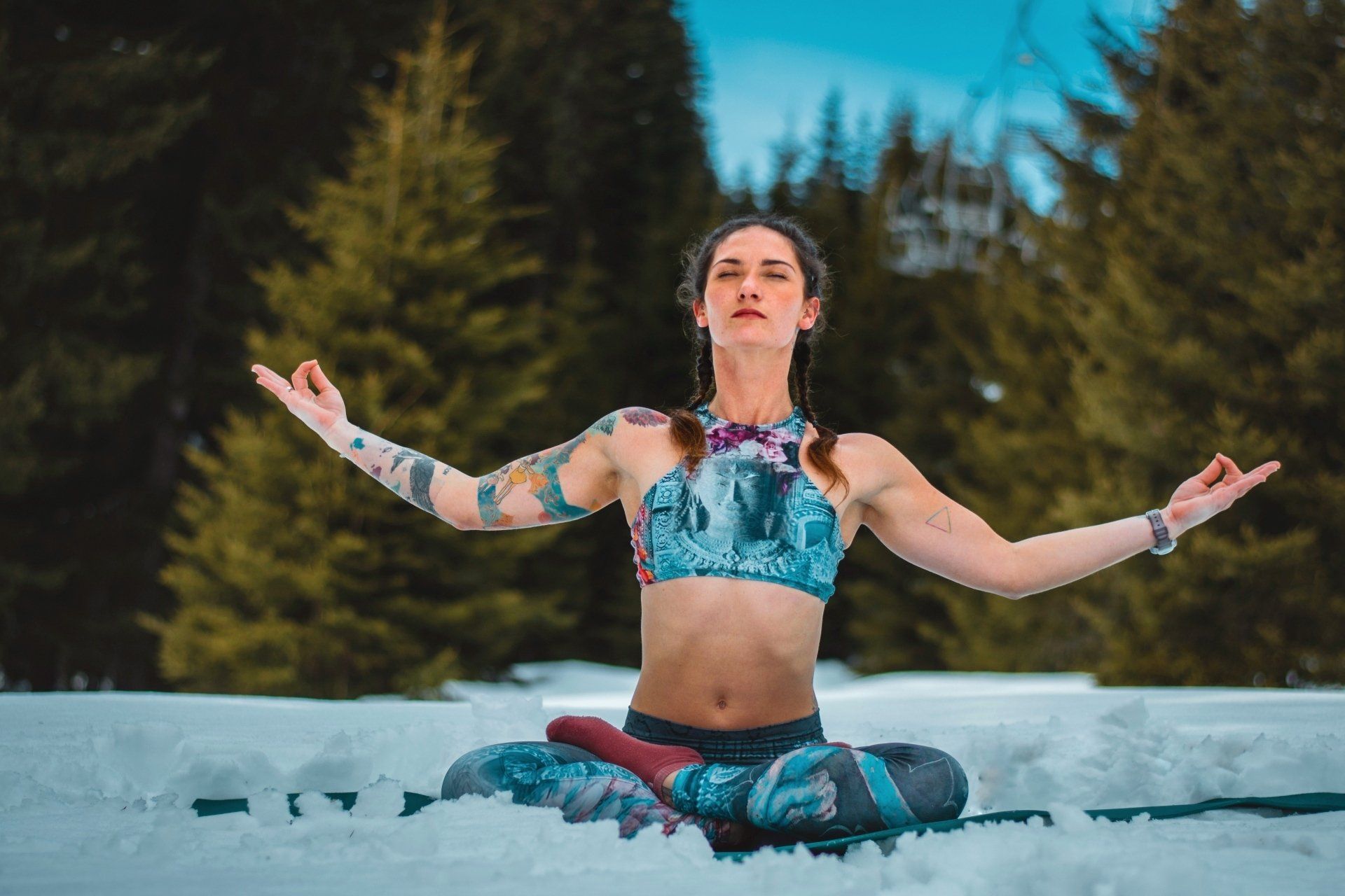 A woman is sitting in a lotus position in the snow.