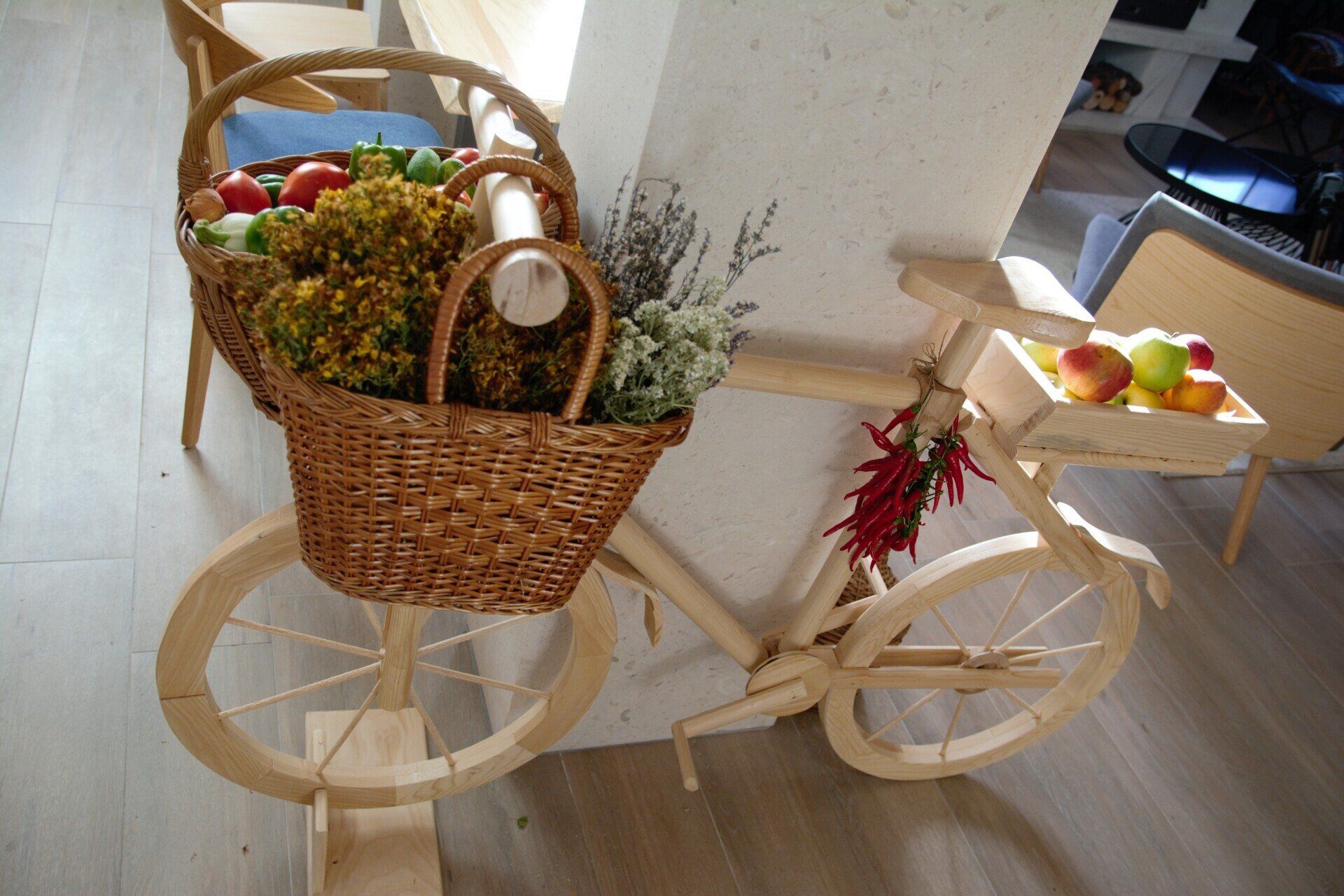 A wooden bicycle with a basket full of fruit and flowers