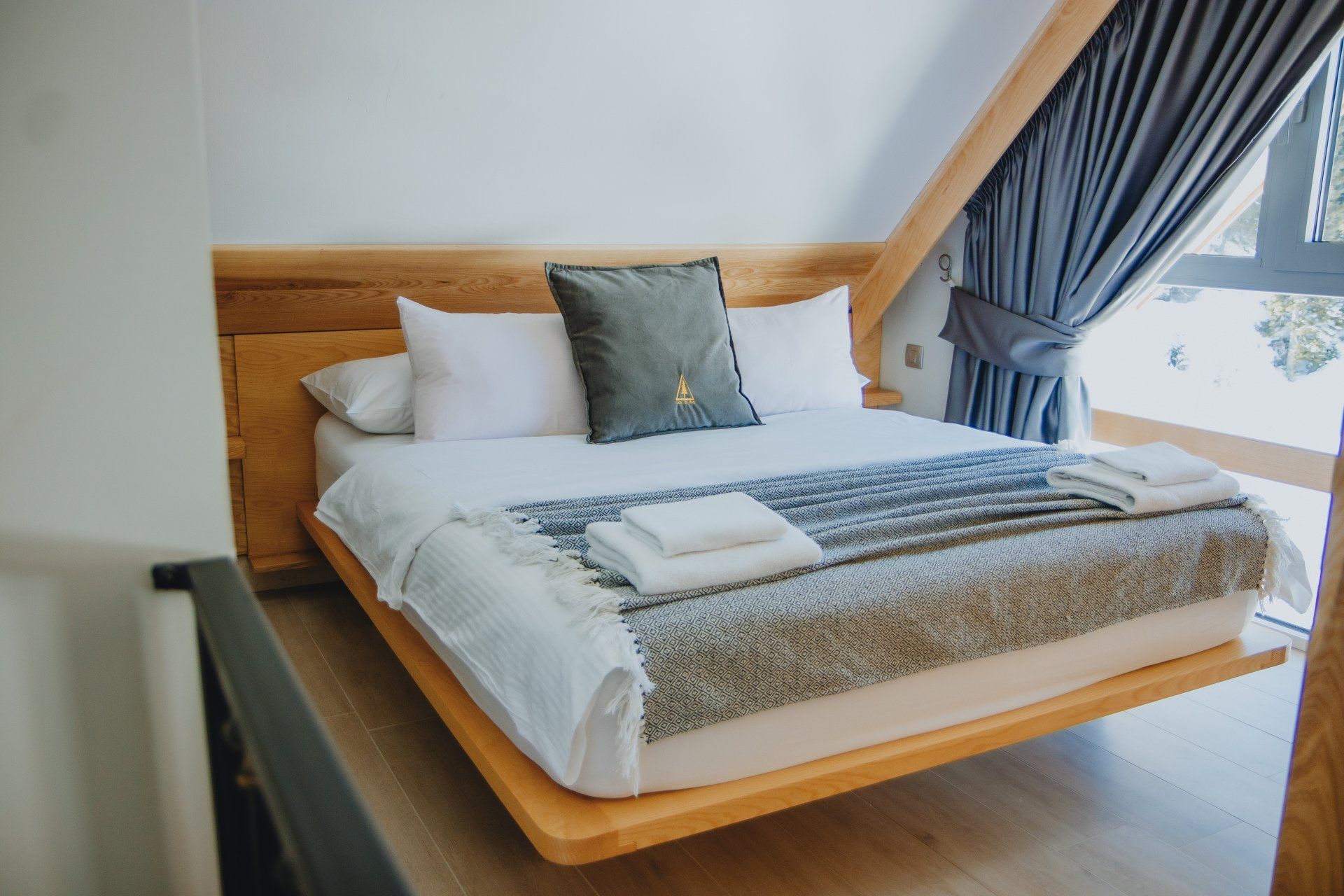 A bed with white sheets and pillows in a bedroom with a window.