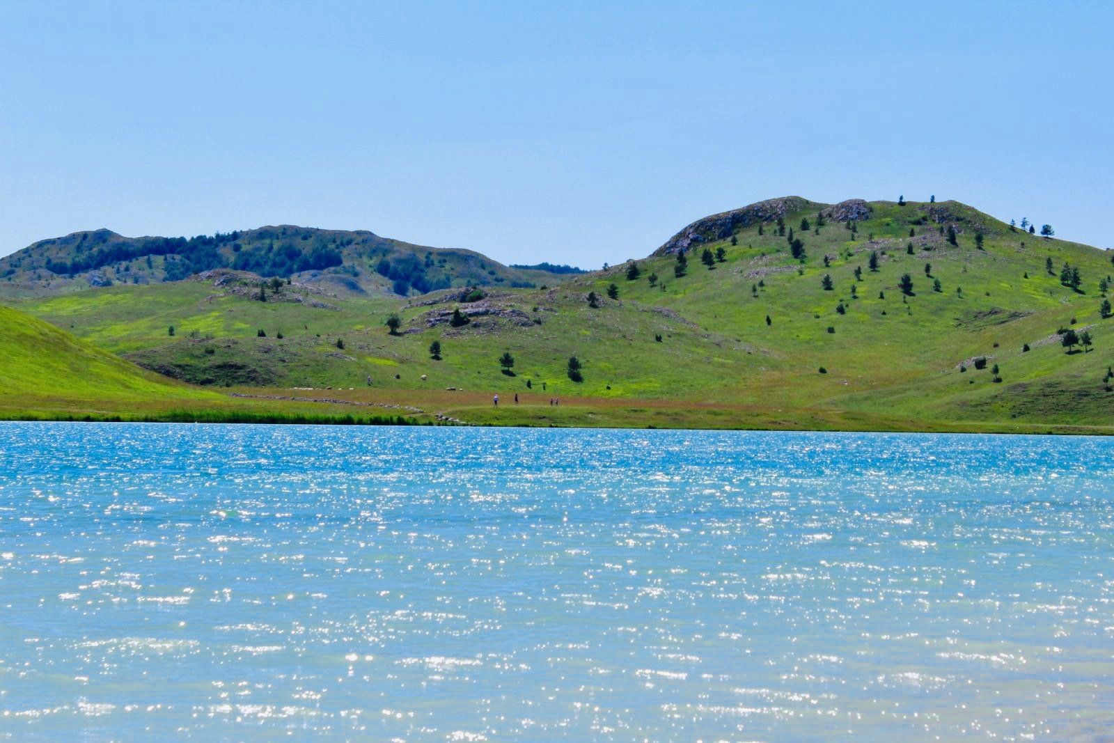 A lake with mountains in the background and a blue sky