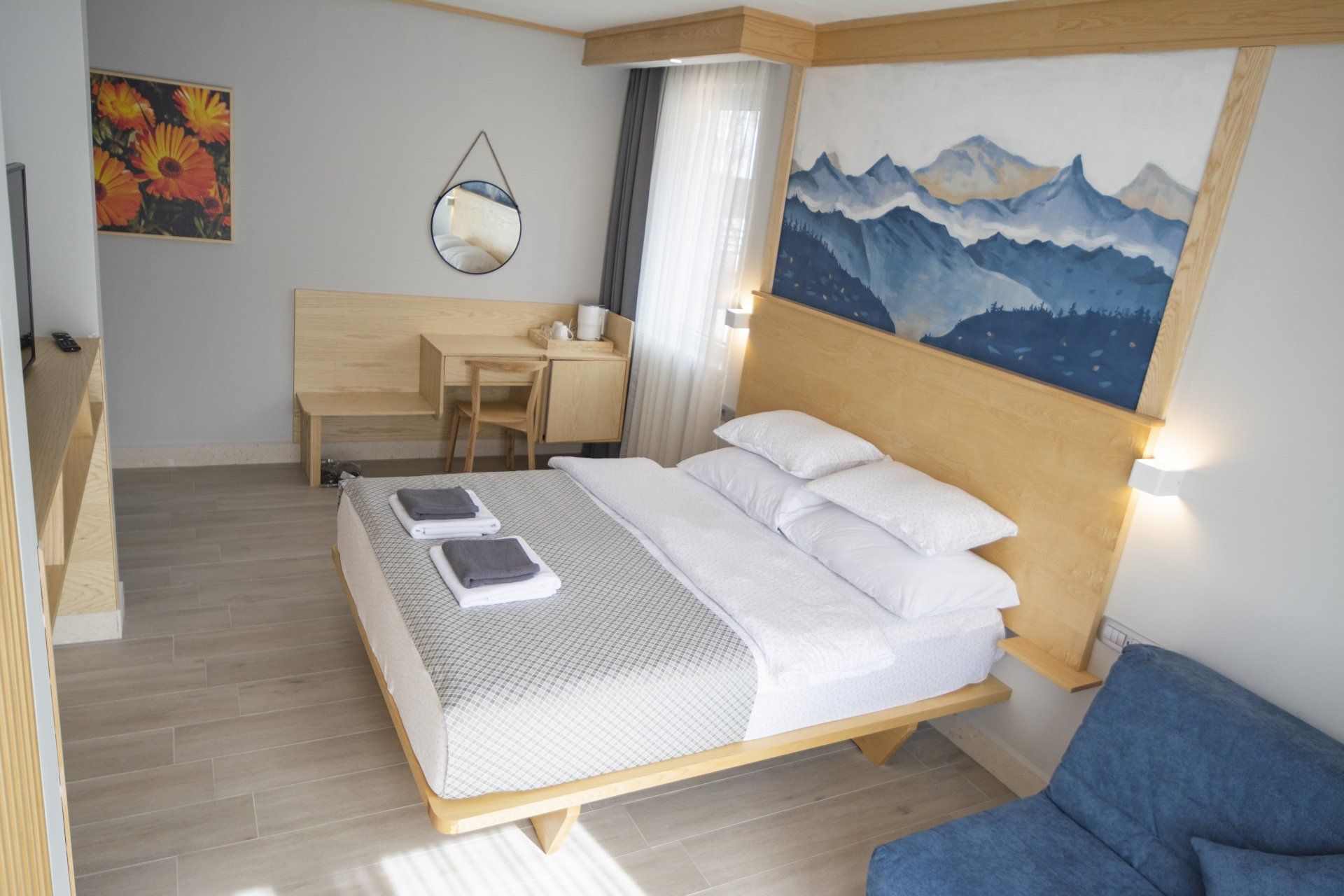 A hotel room with a king size bed, desk with a mirror, chair and couch.