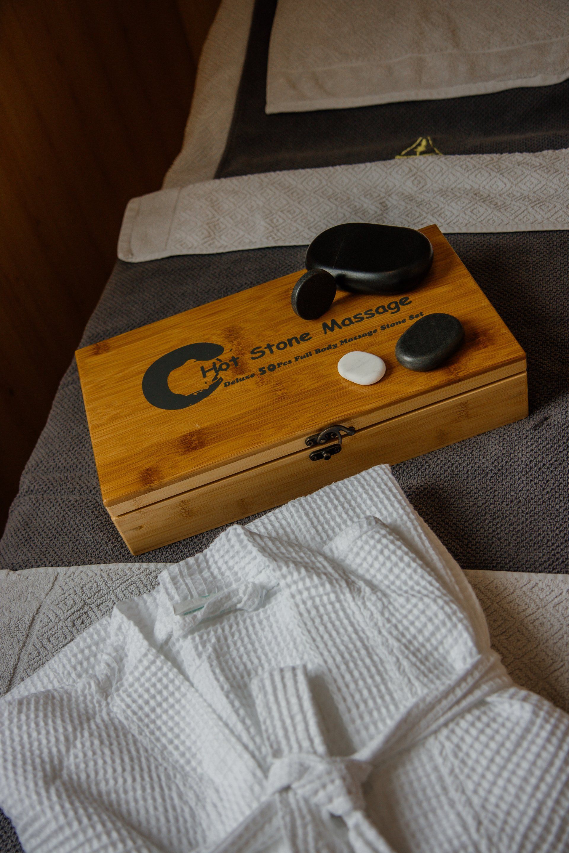 A wooden box sitting on top of a massage bed next to a white robe.