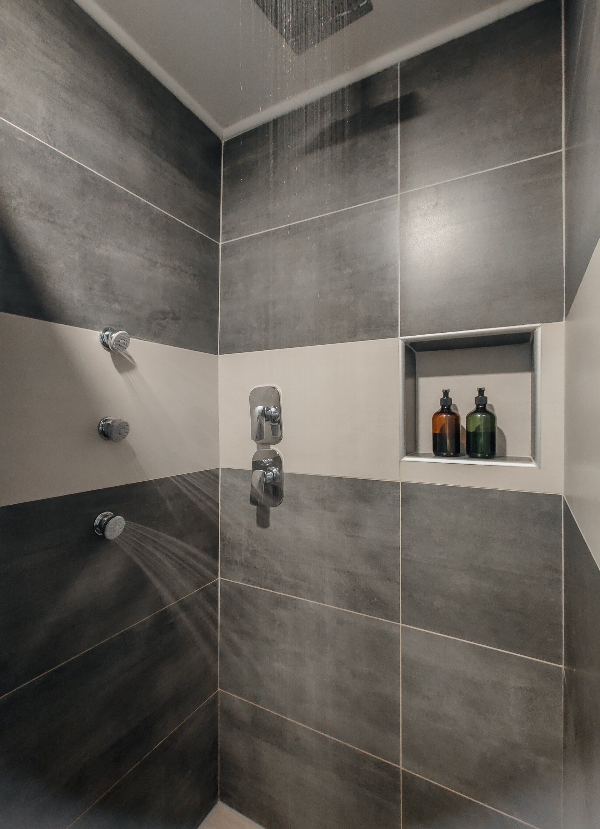 A bathroom with a shower and two bottles of soap on a shelf