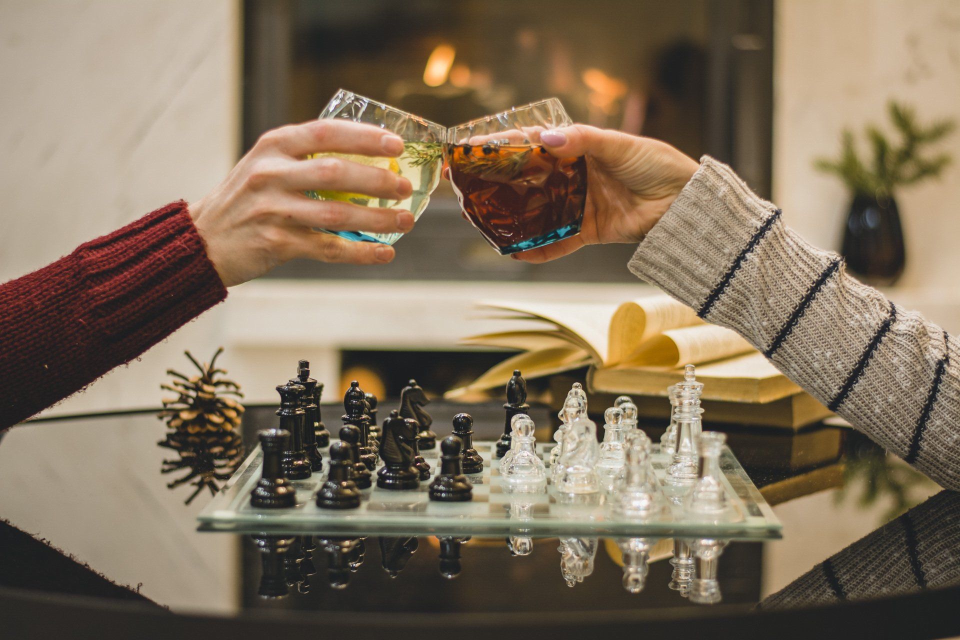 Two people are toasting with drinks over a chess board.