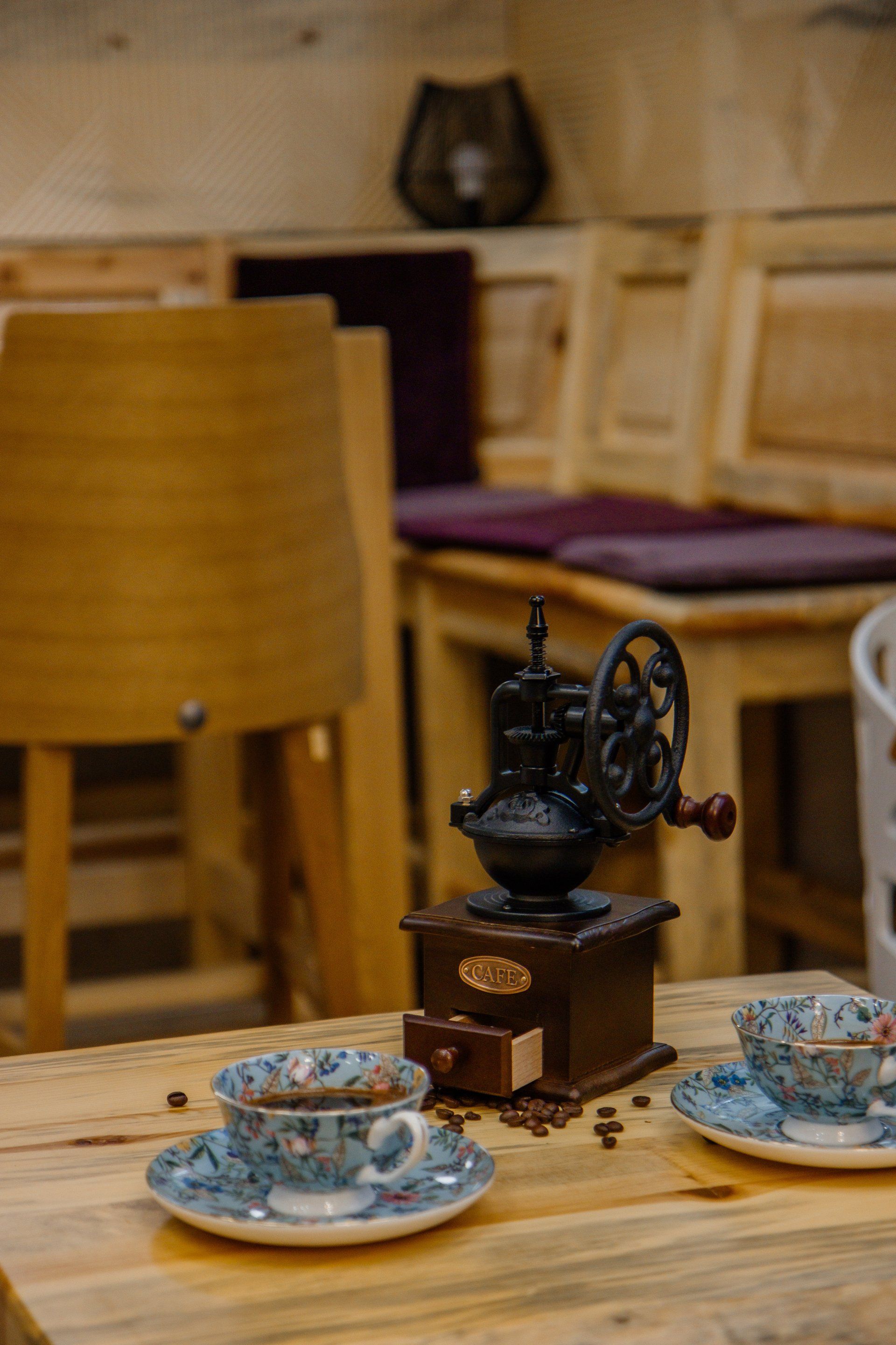 Two cups of coffee and a coffee grinder on a wooden table.