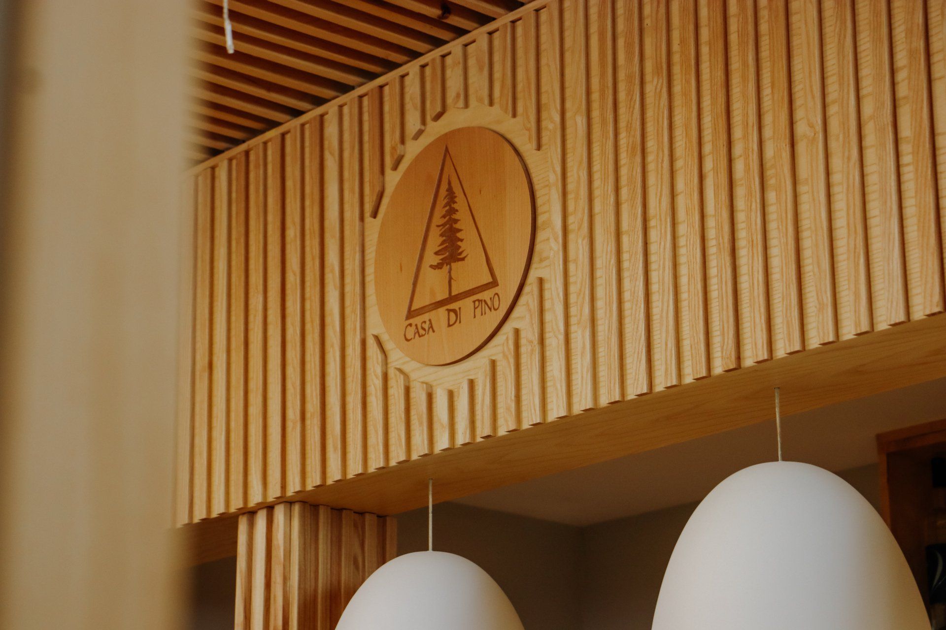 A wooden sign with a tree on it is hanging from the ceiling of a building.