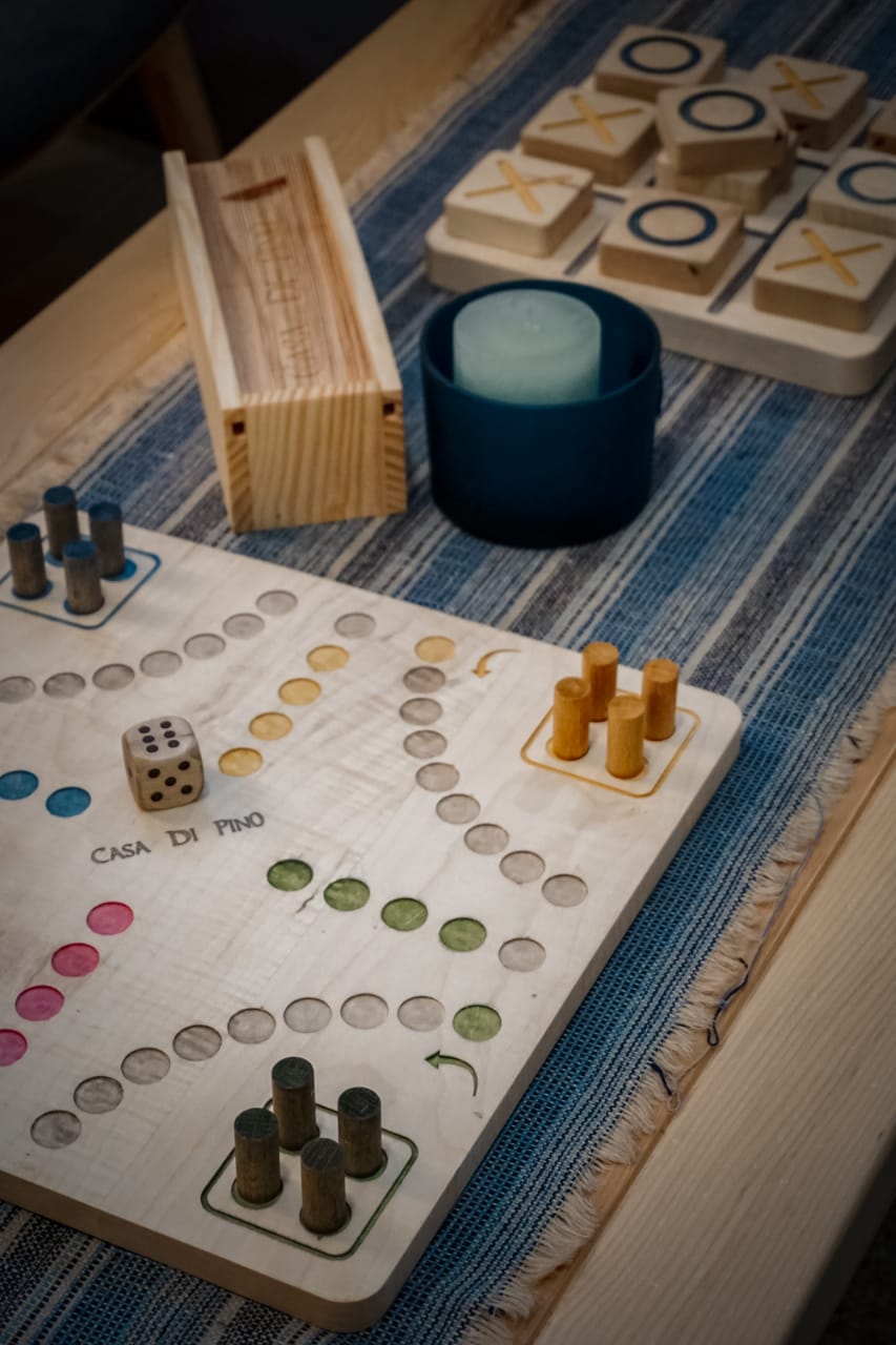 A wooden board game is sitting on a table next to a candle.