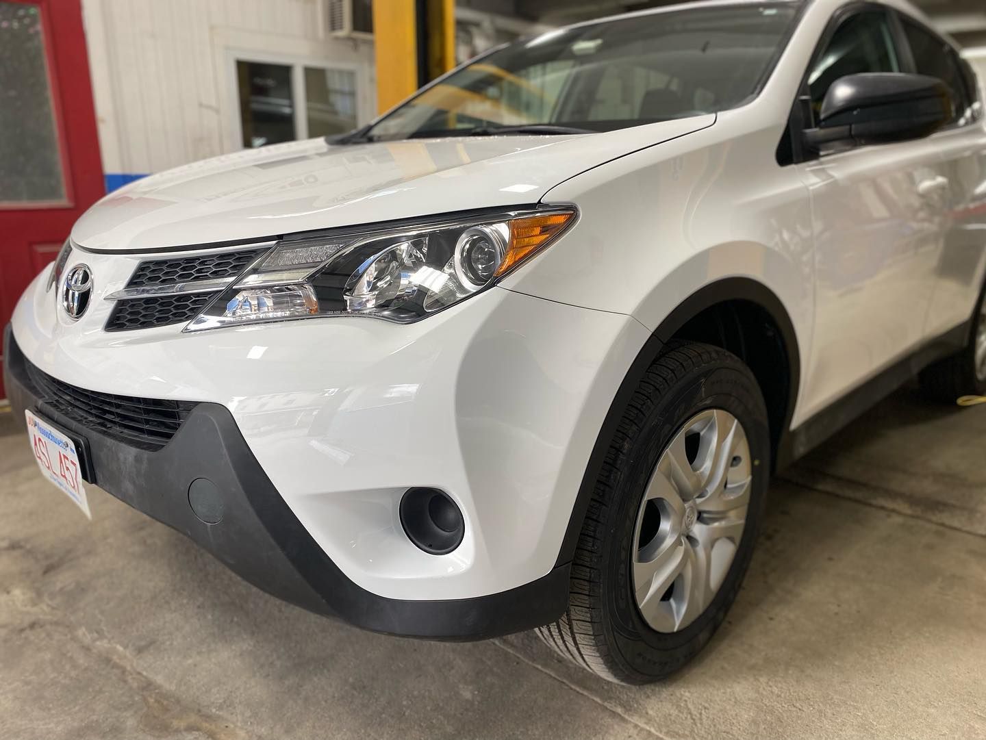 White Toyota RAV4 SUV parked in a garage, close-up of front.