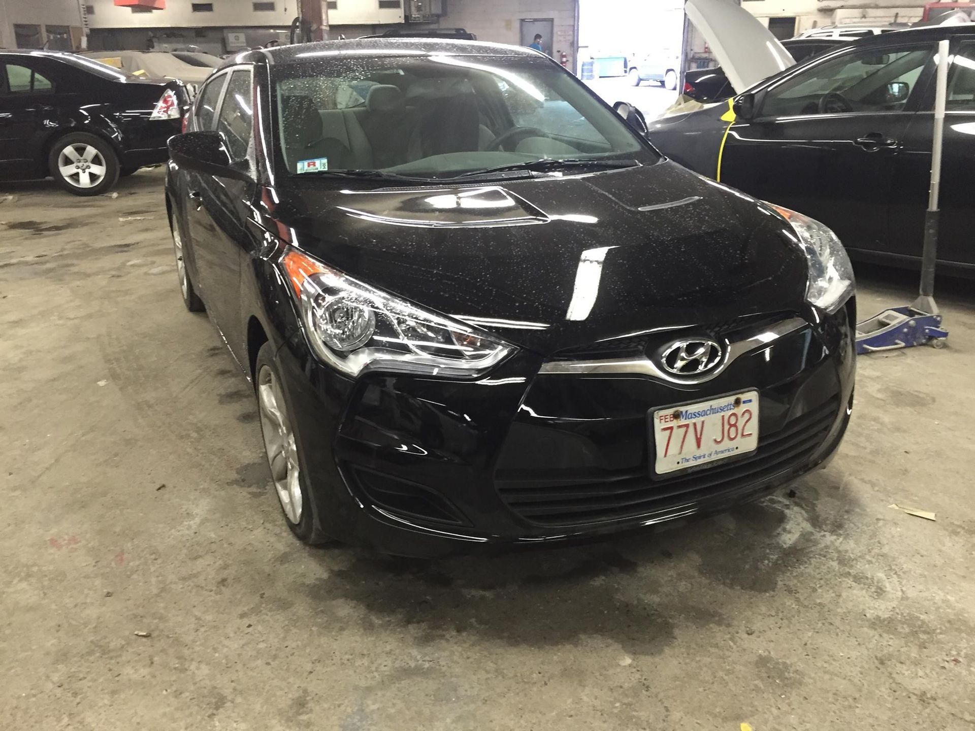 Black Hyundai Veloster in a garage. Massachusetts license plate.