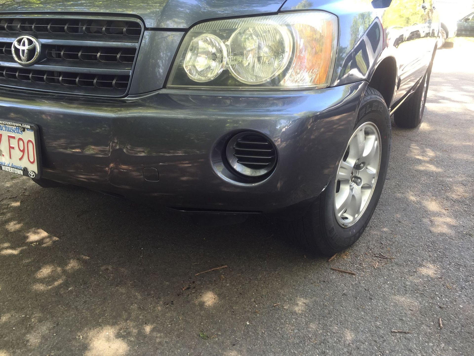Dark gray Toyota Highlander, front view; damaged bumper.