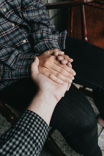 A man and a woman are holding hands while sitting in a chair.