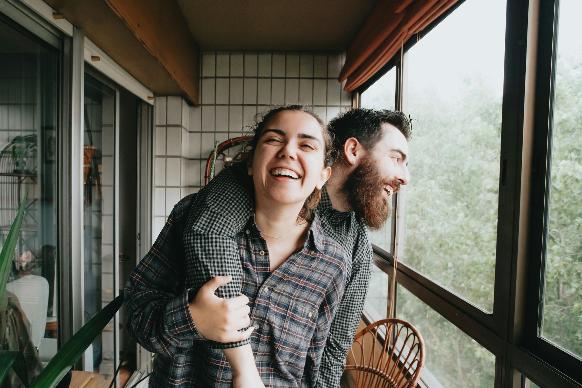 A man is giving a woman a piggyback ride on a balcony.