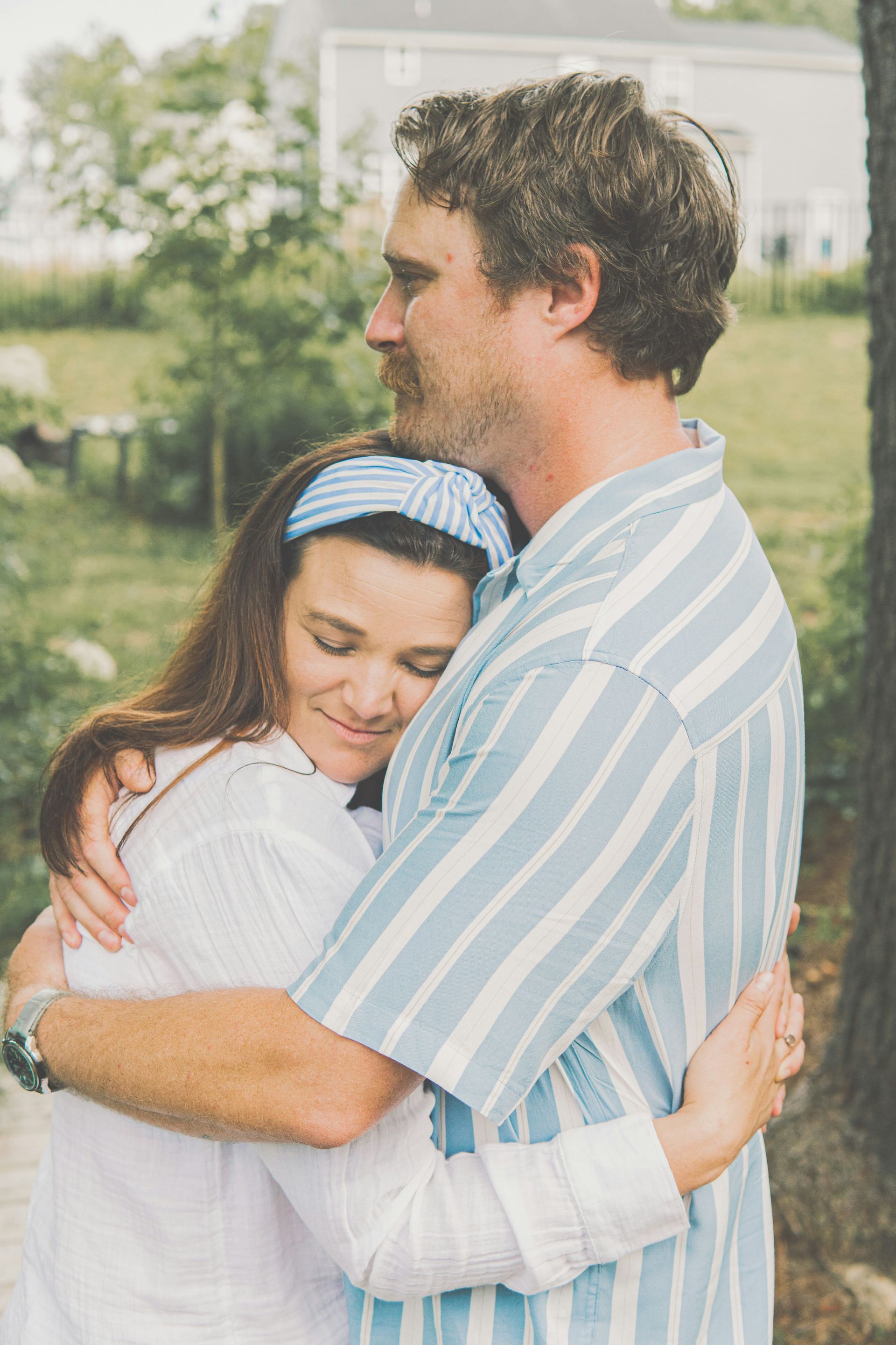 A man and a woman are hugging each other in front of a house.