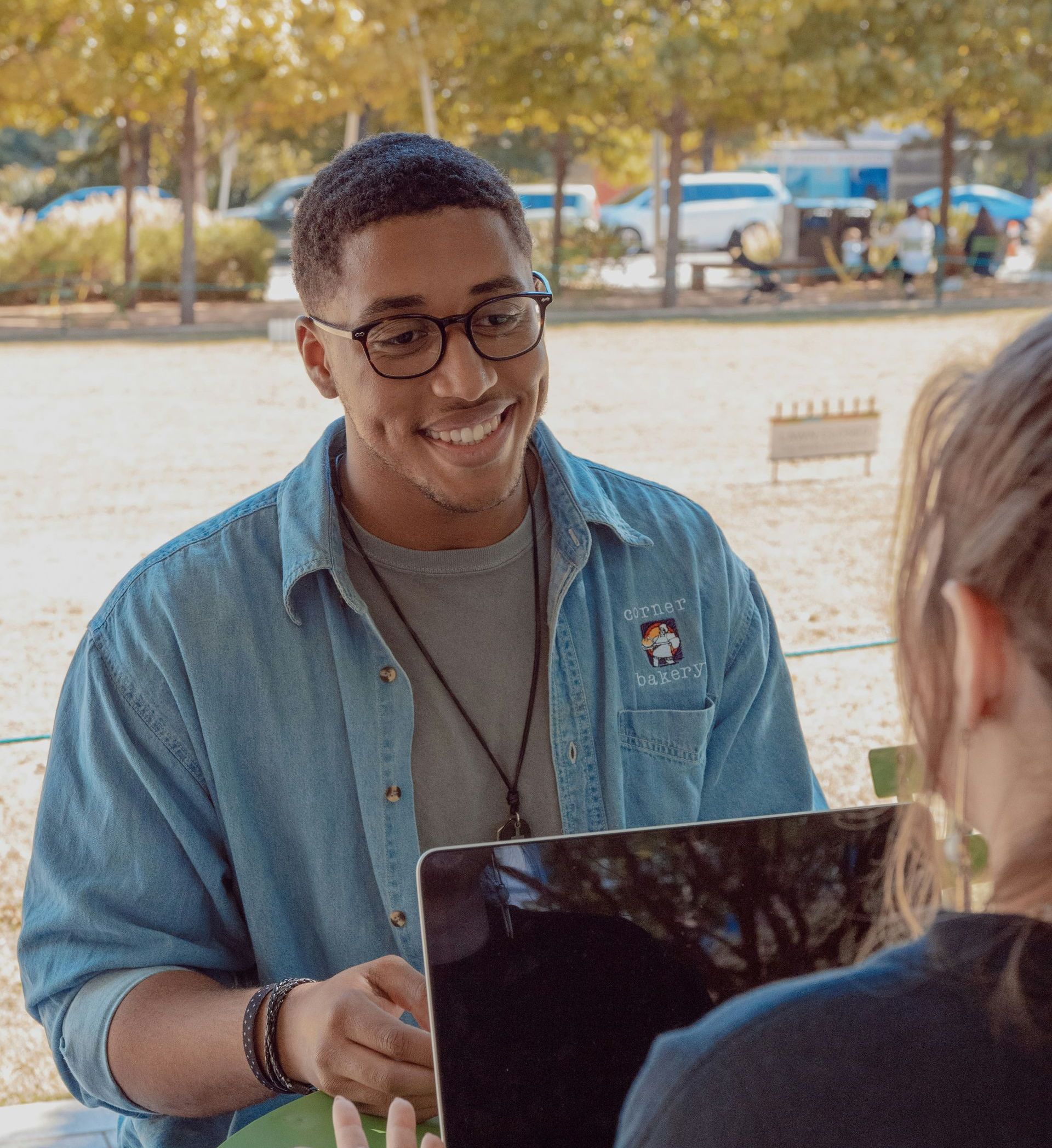 A man wearing glasses is smiling while holding a tablet