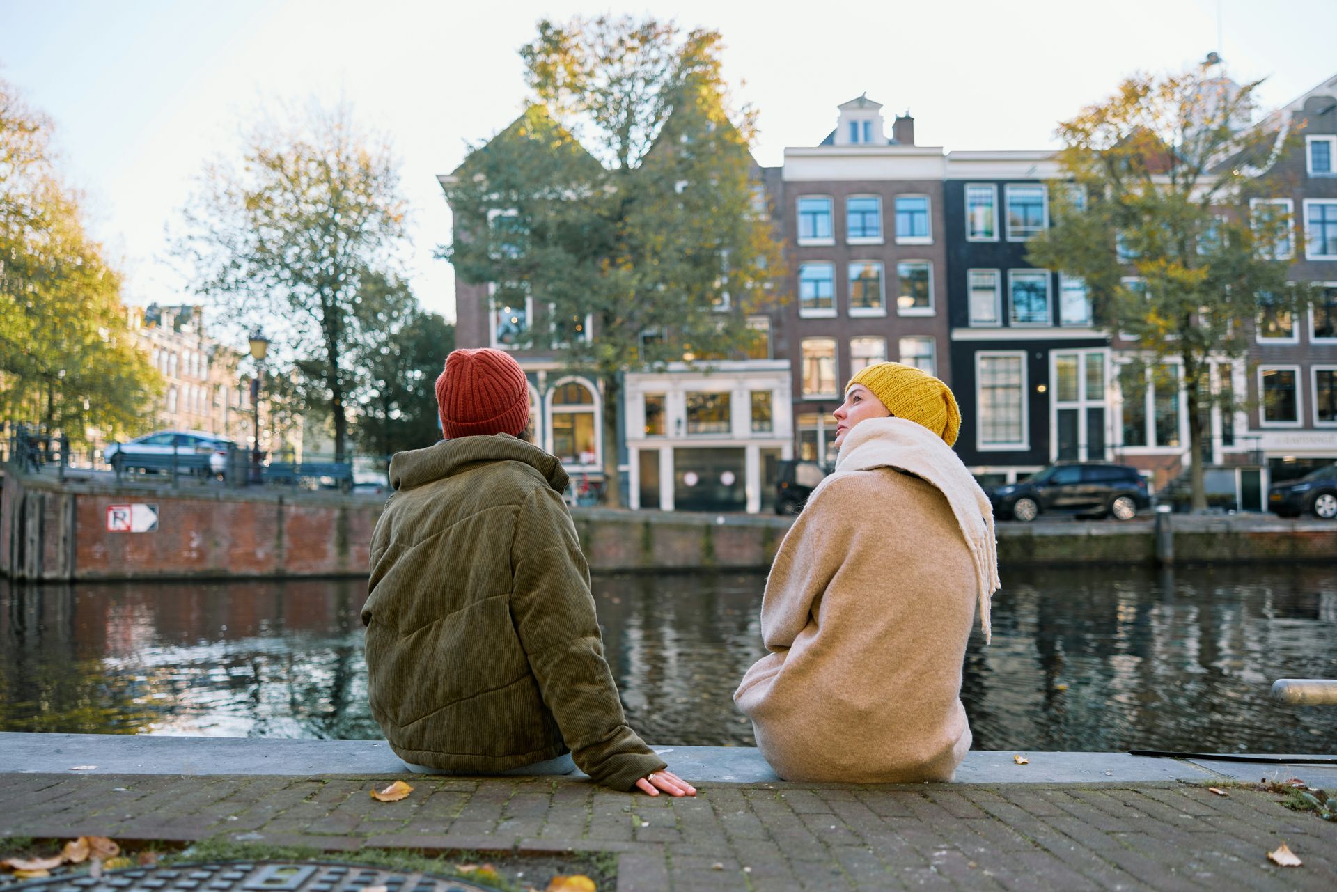 A man and a woman are sitting on a ledge overlooking a river.