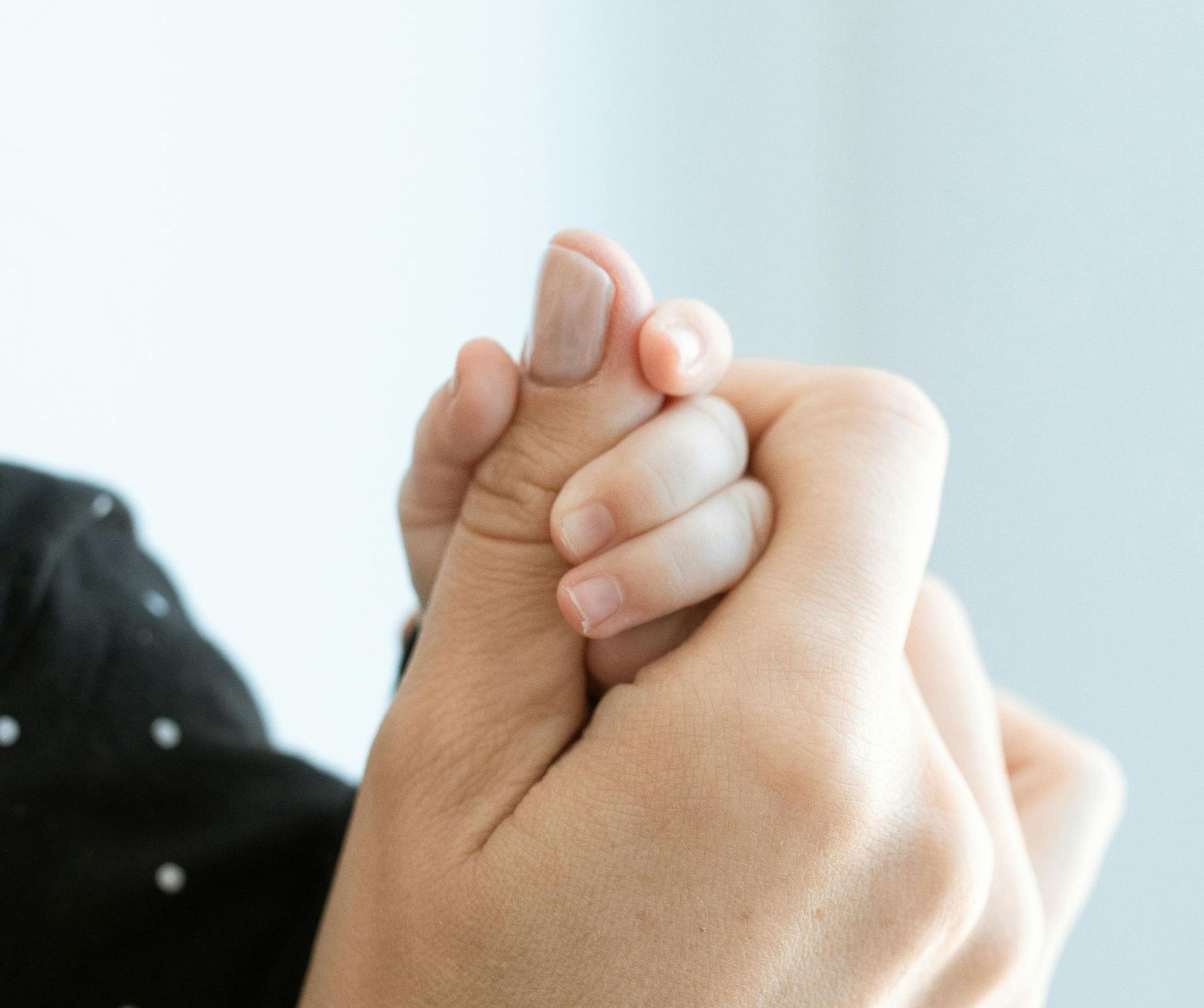 A woman is holding a baby 's hand in her hands.