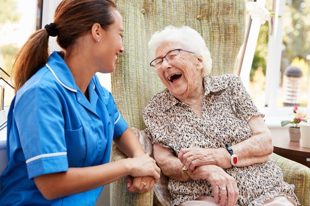 Caregiver laughing along with her elderly patient.