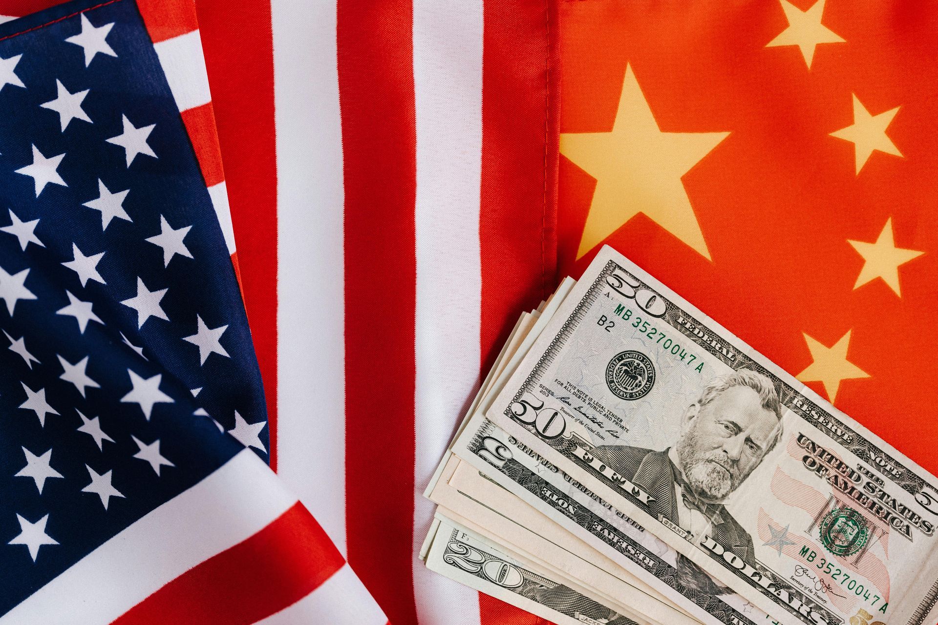 US and China flags with US dollar bills, symbolizing economic relations.