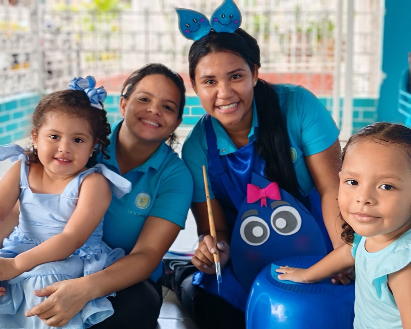 Dos adultos y dos niños con atuendos azules sonriendo. 