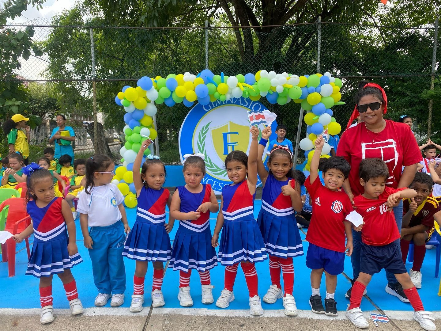 Cuatro estudiantes posan al aire libre cerca de las escaleras de la escuela, vistiendo sudaderas azul marino.