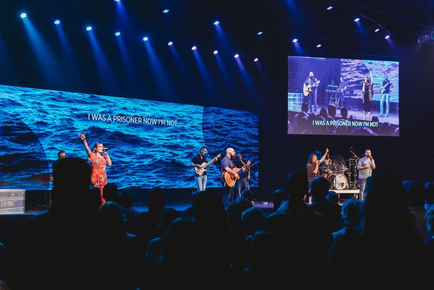 A group of people are standing on a stage in front of a large screen.