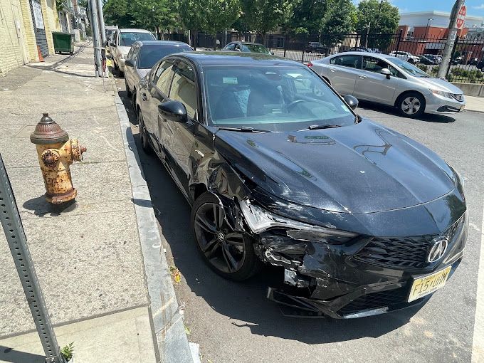 A black car is parked on the side of the road next to a fire hydrant.