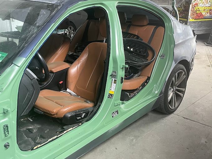 A green car with the doors open and brown seats.