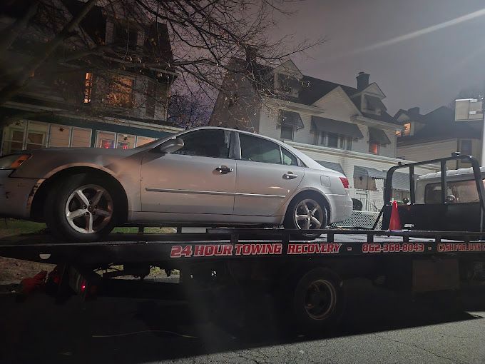 A silver car is sitting on top of a tow truck.