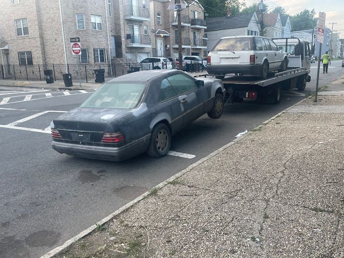 A car is being towed down the street by a tow truck.