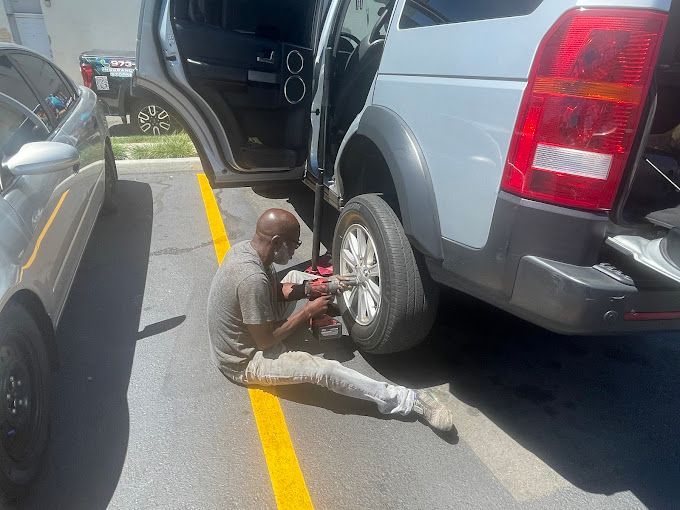 A man is changing a tire on a car in a parking lot.
