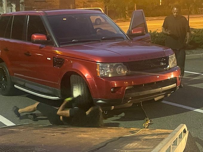A red range rover is being towed by a tow truck.