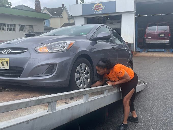 A woman is pushing a car on a tow truck.