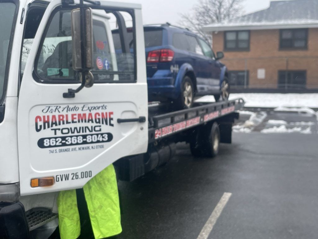 A car is being towed by a charlemagne towing truck