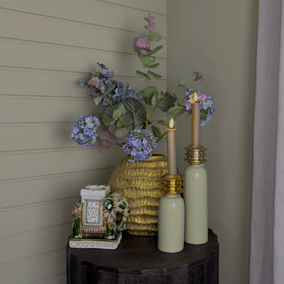 Gouden ribbelvaas gevuld met realistische zijden bloemen in zachte tinten groen, paars en roze