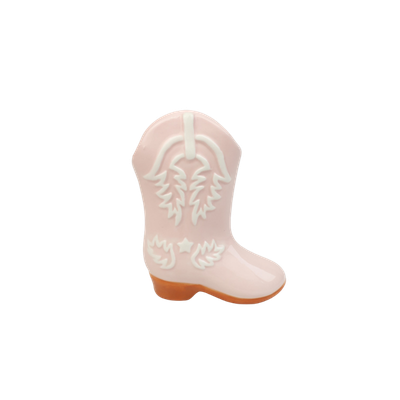 Een lichtroze keramische cowboylaarsdecoratie met witte reliëfdetails en een bruine voet.