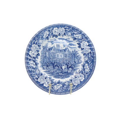 Een decoratief blauw-wit keramisch bord met een afbeelding van een historisch landhuis, figuren te paard en een bloemenrand.