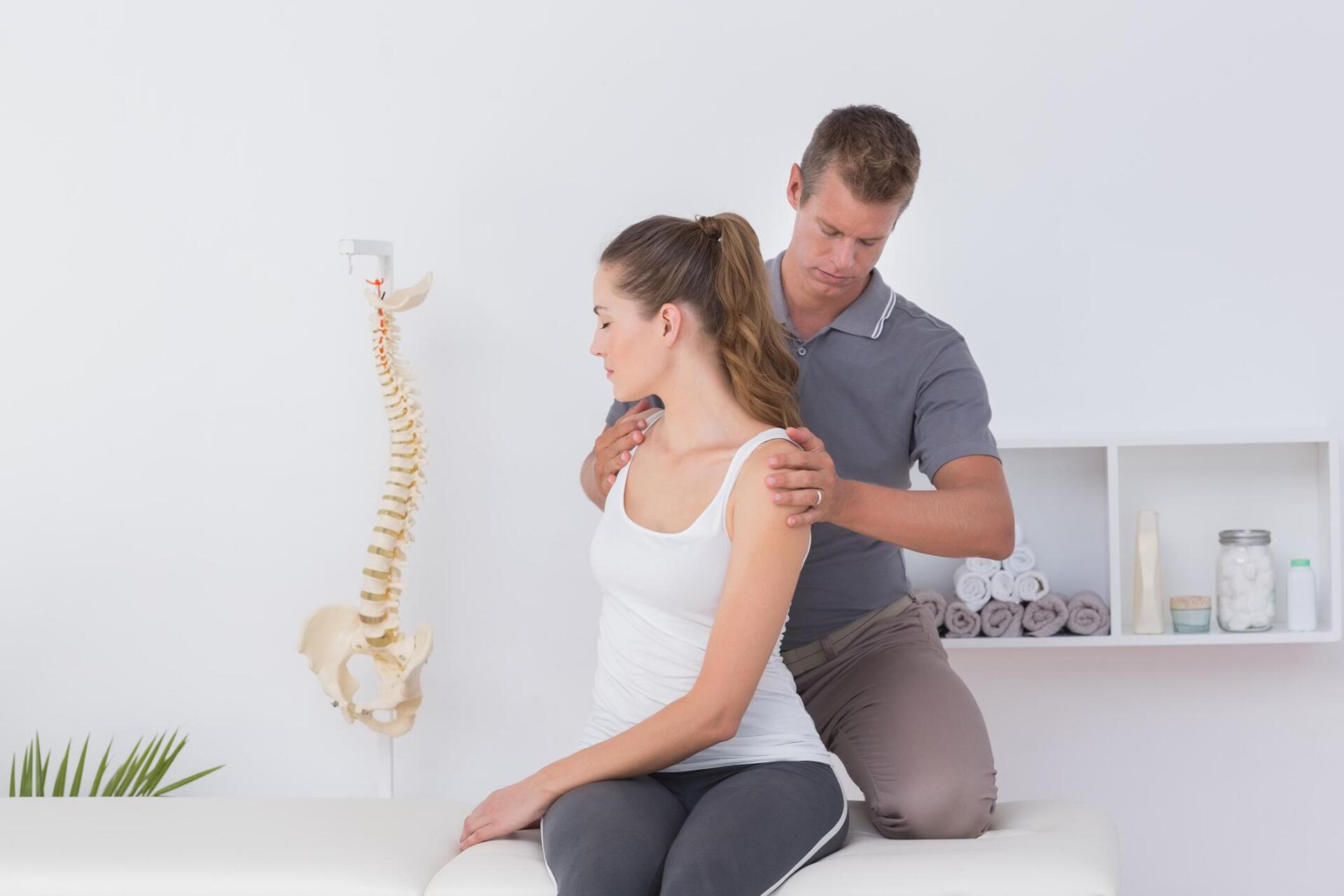 woman sitting while the therapist holds her back