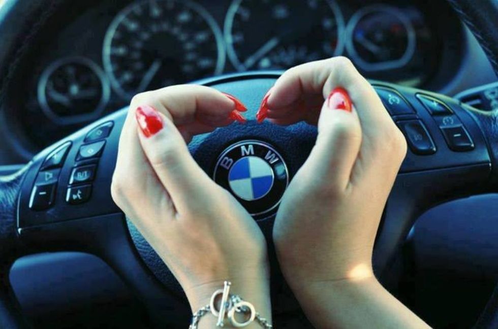 Hands on BMW steering wheel with dashboard gauges in the background
