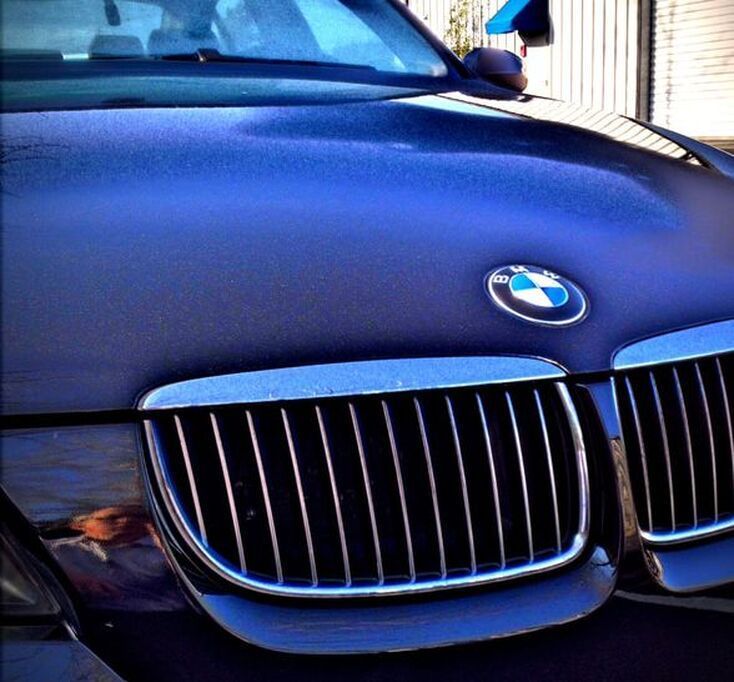 Close-up of a blue BMW front grille and hood with the logo visible