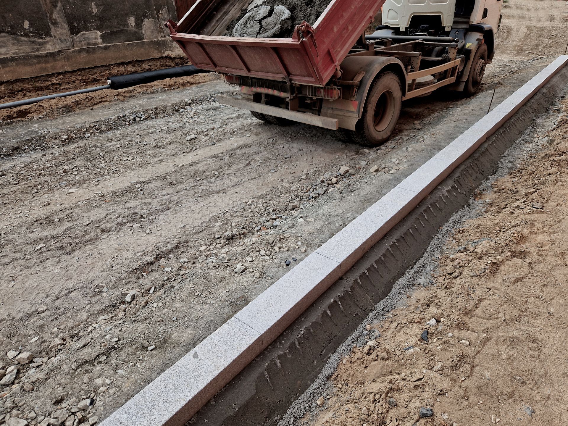 Gravel pathway curves through a grassy field, lined with bricks. Blue stepping stones are visible.