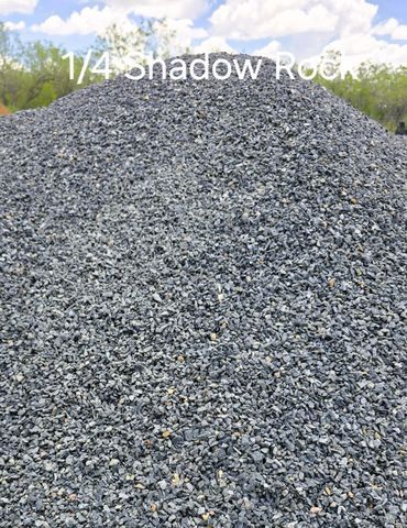Pile of dark gray 1/4 inch shadow rock against a blue sky.