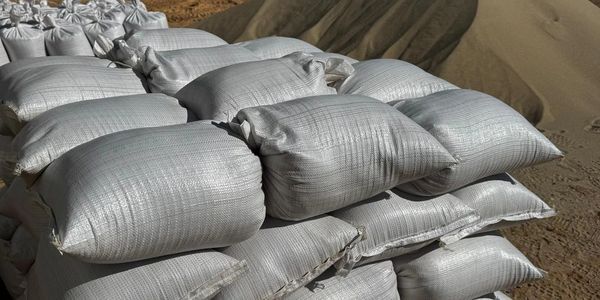White sandbags piled on top of each other, in an outdoor setting.