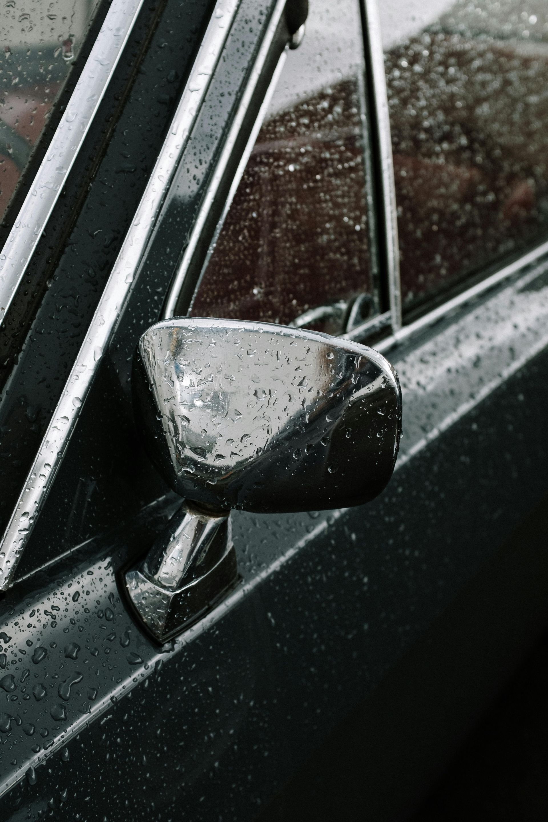 A close up of a car 's side mirror on a rainy day. | All Automotive